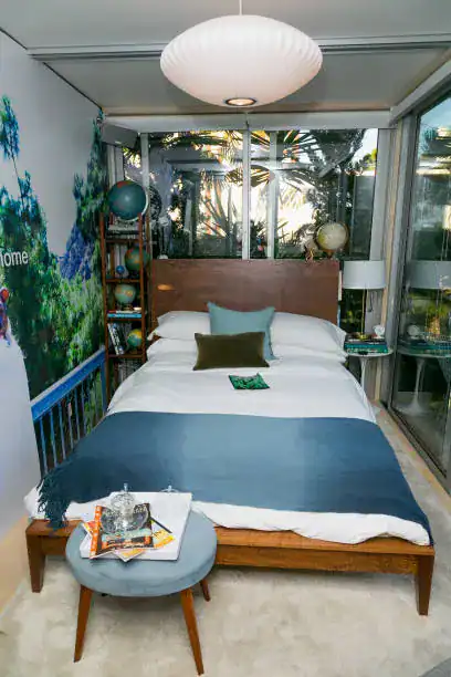 Elegant modern bedroom with a wooden bed, blue bedding, and a glass enclosure.