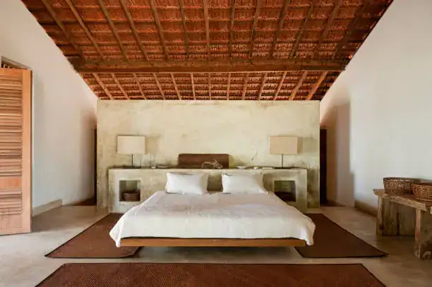 Elegant hotel bedroom with a white bed and rustic wooden ceiling.