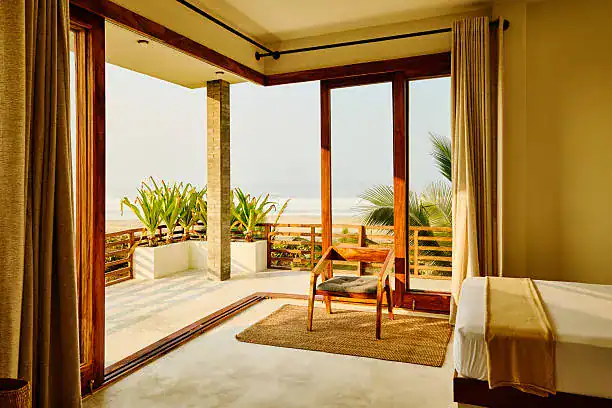 Luxurious hotel balcony with seating and sea view, warm natural light.