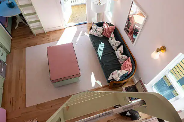 Luxurious living space with pink ottoman and curved sofa under bright natural light.